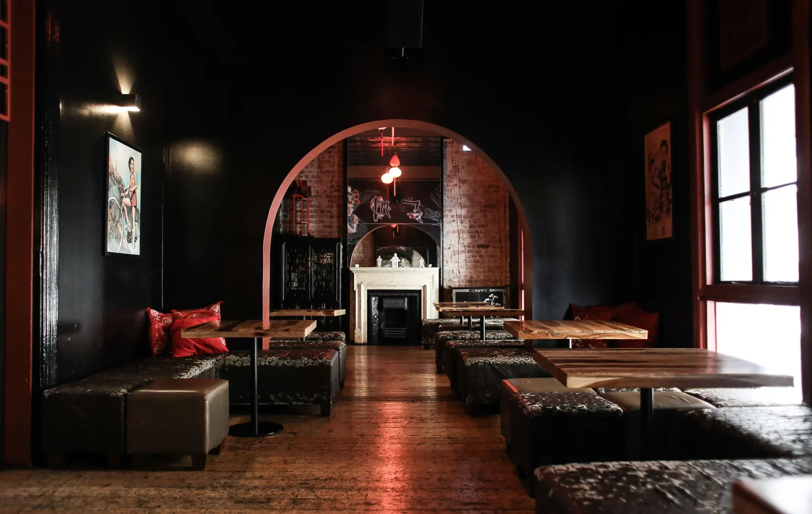 A dark cocktail bar with leather banquettes under a brick arch